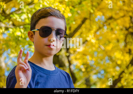 Ein Portrait eines Jungen gegen die Blätter im Herbst. Stockfoto