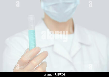 Die Laboratory Assistant hält ein Reagenzglas mit Flüssigkeit in seiner Hand. Einen großen Plan. Stockfoto