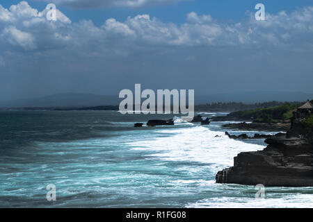 Landschaft der Insel Bali Ufer mit dunklen blauen Indischen Ozean, Wellen und schwarzen Klippe mit Tempel Stockfoto