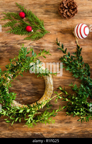 Buchsbaum Weihnachten Kranz. DIY Weihnachten Dekoration Konzept. Schreibtisch aus Holz Draufsicht. Stockfoto