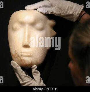 Bonhams. London, Großbritannien. 12 Nov, 2018. Ein Mitglied des Personals hält' Der Mann hinter der Maske', ein von Henry Moore's Êmasterpiece (British, 1898-1986). (Schätzung: £ 1,000,000-1, 500.000). Die Arbeit ist eine von 12 bekannten, kleinen Schnitzereien von Moore mit dem Titel Maske, und, einzigartig, ist der Einzige aus Alabaster geschnitzt. Bonhams Moderne Britische und Irische Kunst Vorschau. Die Auktion vom 14. November 2018 abgehalten werden. Credit: Dinendra Haria/Alamy leben Nachrichten Stockfoto