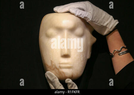 Bonhams. London, Großbritannien. 12 Nov, 2018. Ein Mitglied des Personals hält' Der Mann hinter der Maske', ein von Henry Moore's Êmasterpiece (British, 1898-1986). (Schätzung: £ 1,000,000-1, 500.000). Die Arbeit ist eine von 12 bekannten, kleinen Schnitzereien von Moore mit dem Titel Maske, und, einzigartig, ist der Einzige aus Alabaster geschnitzt. Bonhams Moderne Britische und Irische Kunst Vorschau. Die Auktion vom 14. November 2018 abgehalten werden. Credit: Dinendra Haria/Alamy leben Nachrichten Stockfoto