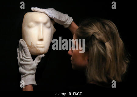 Bonhams. London, Großbritannien. 12 Nov, 2018. Mitarbeiter hält' Der Mann hinter der Maske', ein von Henry Moore's-Meisterwerk (British, 1898-1986). (Schätzung: £ 1,000,000-1, 500.000). Die Arbeit ist eine von 12 bekannten, kleinen Schnitzereien von Moore mit dem Titel Maske, und, einzigartig, ist der Einzige aus Alabaster geschnitzt. Bonhams Moderne Britische und Irische Kunst Vorschau. Die Auktion vom 14. November 2018 abgehalten werden. Credit: Dinendra Haria/Alamy leben Nachrichten Stockfoto