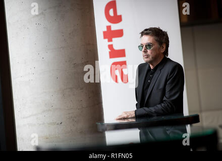 12. November 2018, Hamburg: Der Musiker Jean-Michel Jarre steht an einem Tisch in einem Fotoshooting vor einer Pressekonferenz über "Winter Moon' bei Arte. Vom 6. bis 20. Januar 2019, Arte feiert den 50. Jahrestag der ersten bemannten Mondlandung mit seinem Programm. Foto: Christian Charisius/dpa Stockfoto