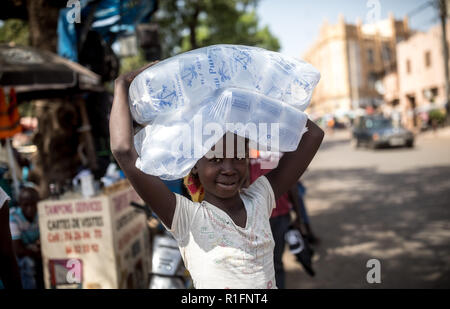 Bamako, Mali. 12 Nov, 2018. Ein Mädchen trägt eine Tasche von Trinkwasser Teile durch Bamako, der Hauptstadt von Mali. Von der Leyen: In Afrika ist zu einem dreitägigen Besuch und auch Besuche der Soldaten der Bundeswehr. Quelle: Michael Kappeler/dpa/Alamy leben Nachrichten Stockfoto