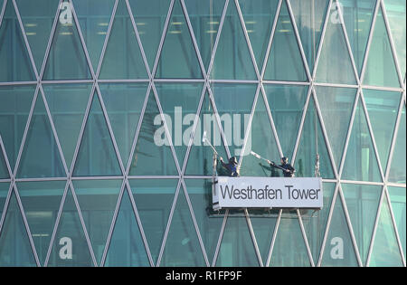 12. November 2018, Hessen, Frankfurt/Main: Arbeiter Reinigen der Glasfassade der Westhafen Tower in Frankfurt mit Hochdruckreinigern. Da das Bürogebäude ähnelt einem traditionellen Apfelwein Glas, Frankfurter nennen es auch "Die gerippten'. Foto: Arne Dedert/dpa Stockfoto