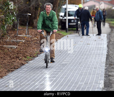 12. November 2018, Nordrhein-Westfalen, Erftstadt: ein Mann, der mit seinem Fahrrad Fahrräder auf dem First Solar Radweg in Deutschland. Die Solarzellen auf Fahrbahn Platten montiert generieren Sonnenenergie auf dem 100 Meter langen Solar Test Track, der in das Stromnetz eingespeist wird. Foto: Henning Kaiser/dpa Stockfoto