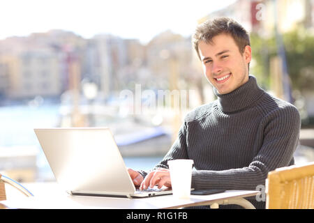 Glückliche Menschen mit einem Laptop, Kamera in einem Café in einem Port Stockfoto