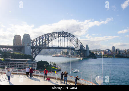 Die Passagiere genießen Sie den schönen Blick auf die Wahrzeichen von Sydney Harbour Bridge vom Deck eines Kreuzfahrtschiffes an der Sydney Cove Passenger Terminal angedockt. Stockfoto