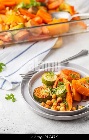Gebackene Gemüse (Karotten, Zucchini, Kartoffel, Kürbis) mit Kichererbsen. Auf Basis pflanzlicher Ernährung Konzept. Stockfoto