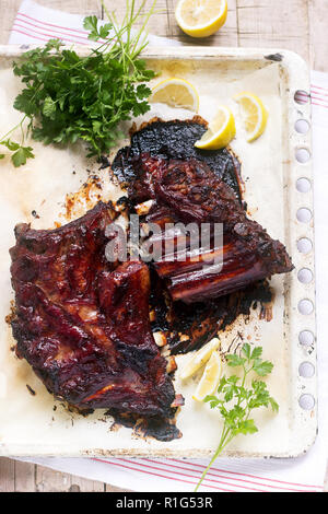 Appetitlich gebackene verglaste Kalb- oder Schweinefleisch Rippen mit Zitrone und Kräutern serviert. Selektive konzentrieren. Stockfoto