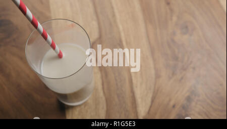 Hafermilch in Glas mit rotem Papier Stroh auf Holz Hintergrund mit Kopie Raum, große Foto Stockfoto