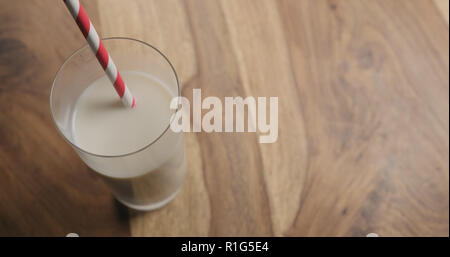 Hafermilch in Glas mit rotem Papier Stroh auf Holz Hintergrund mit Kopie Raum, große Foto Stockfoto
