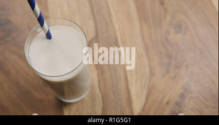 Hafermilch in Glas mit blauem Papier Stroh auf Holz Hintergrund mit Kopie Raum, große Foto Stockfoto