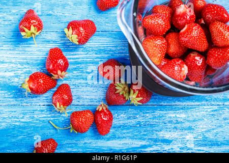 Eine reife Erdbeere in eine Schüssel mit einem Mixer auf einem Holztisch. Erdbeere smoothies Vorbereitung Stockfoto