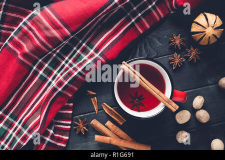 Weihnachten Glühwein mit Gewürzen in rot Tasse auf Holz- Hintergrund. Stockfoto