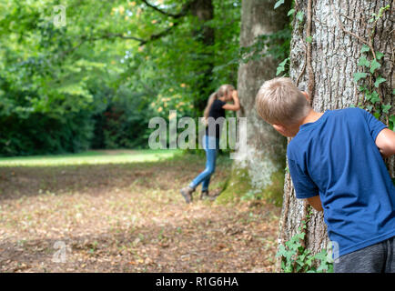 Junge Kinder spielen Verstecken und im Wald suchen Stockfoto