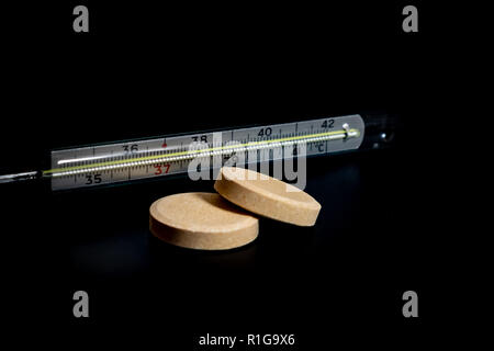 Thermometer auf schwarzem Hintergrund und kalten Pillen 2018 Stockfoto