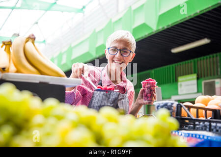 Portrait der älteren Frau verkauft Himbeeren auf dem Markt Stockfoto