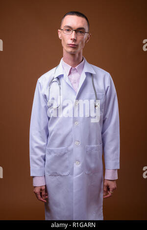 Jungen schönen androgynen Menschen Arzt gegen braunen Hintergrund Stockfoto