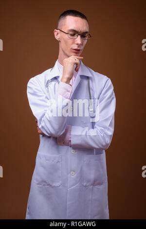 Jungen schönen androgynen Menschen Arzt gegen braunen Hintergrund Stockfoto