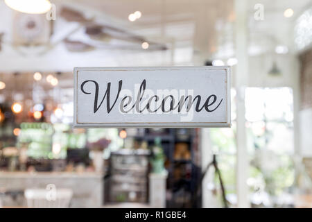 Label Willkommen ist es von altem Holz. Schild close-up Willkommen durch das Glas von einem Café nebenan. Stockfoto