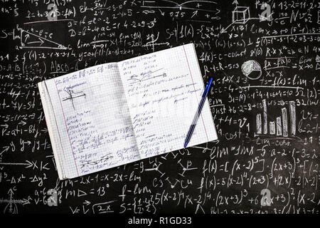 Eine schriftliche Notebook mit einem Stift auf dem Hintergrund der Board mit Beispiele und Formeln Stockfoto