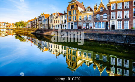 Sonnenuntergang über einer Reihe von Häusern, die auf die Wasseroberfläche ein Kanal im historischen Stadtzentrum von Middelburg in der Provinz Zeeland, Holland spiegeln Stockfoto