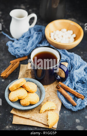 Blau emailliert Tasse Tee, Zimtstangen, Anis Sterne und Shortbread auf einem dunklen Hintergrund Stockfoto