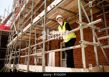 Männliche Bauarbeiter, Polier oder Architekt auf Gerüsten an der Baustelle mit Zwischenablage Stockfoto