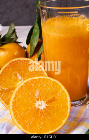 Flach Ansicht von Orangensaft in ein Glas und reife Orangen Obst, in Blau und Weiß Serviette, über rustikale Hintergrund. Stockfoto