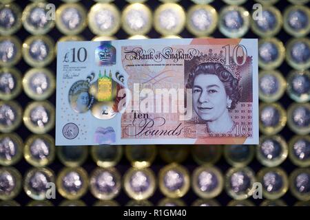 Das neue Polymer £ 10 Hinweis mit Jane Austen, mit der neuen £ 1 Münzen im Hintergrund Stockfoto