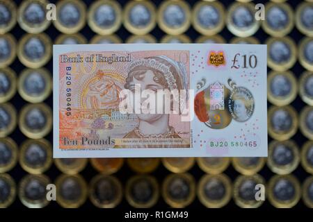 Das neue Polymer £ 10 Hinweis mit Jane Austen, mit der neuen £ 1 Münzen im Hintergrund Stockfoto