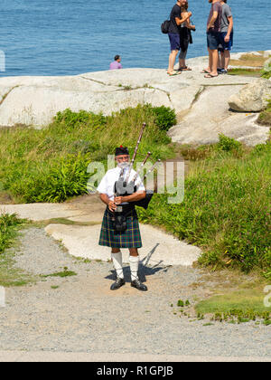 Ein Dudelsackpfeifer teilt seine Musik, spielen an der berühmten Peggy Point Lighthouse, Peggy's Cove, Nova Scotia, Kanada. Stockfoto