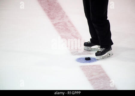 Schwarz hockey puck und Schiedsrichter Beine auf der Eisbahn. Winter Sport. Stockfoto