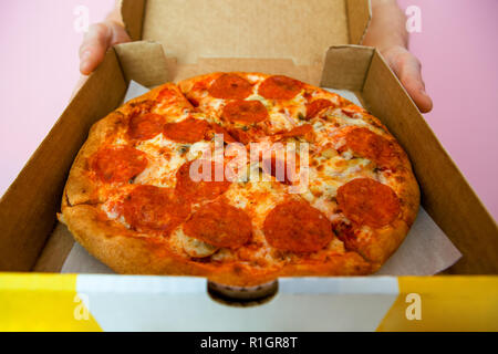 Foto von Pizza in Feld-, Kurier- und Hände Stockfoto