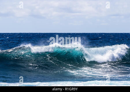 Welle brechen in der Nähe der Ufer auf South Point, auf Hawaii Big Island. Schaum auf der Welle klar blau-grüne Wasser; Pazifik im Hintergrund. Stockfoto