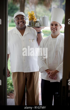 Porträt eines erwachsenen Mannes und einer jungen erwachsenen männlichen Chef holding Zimmerservice. Stockfoto