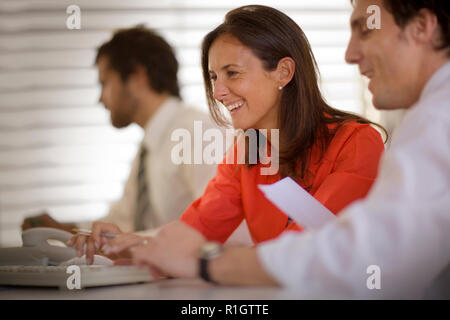 Lächelnd Mitte - Erwachsene geschäftsfrau an einem Schreibtisch mit einem männlichen Kollegen arbeiten. Stockfoto