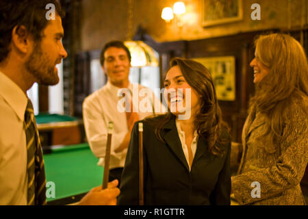 Lächelnde junge Erwachsene Business woman holding einen Pool cue während in einem Pool Hall mit drei Kollegen. Stockfoto