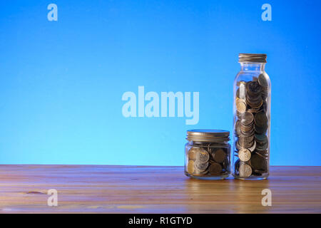 Speichern Konzept mit Mason jar, Münzen und Sparschwein auf blauem Hintergrund. Stockfoto