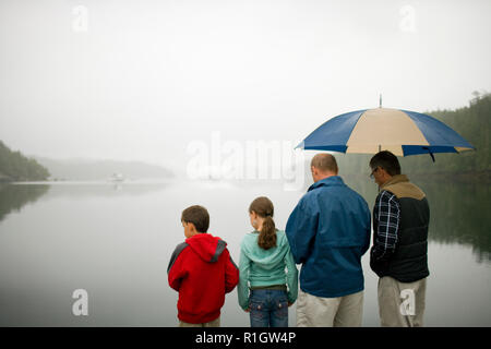 Gruppe von Personen, die über einen See im Regen suchen. Stockfoto