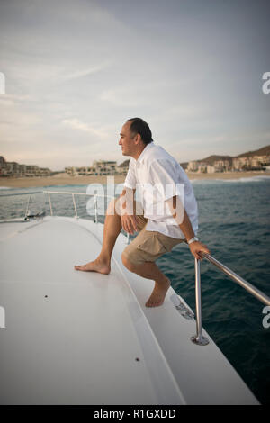 Mitte - erwachsener Mann gegen die Reling eines Schiffes in den Ozean lehnend. Stockfoto