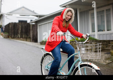 Lächelnden jungen Frau, retro Fahrrad auf eine leere Vorstadtstraße. Stockfoto