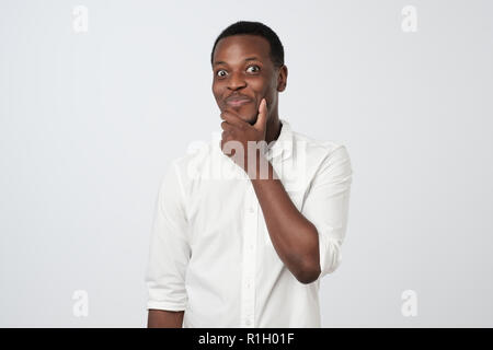 Sly , afrikanischer Mann Kinn Berühren mit dem Finger und Wegsehen. Hübscher Kerl denken. Stockfoto