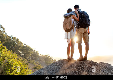 Ansicht der Rückseite des wandern Paar mit Rucksack zusammen stehend auf Hügel genießen die schöne Landschaft. Mann und Frau im Freien auf Wandern stehen auf einer Ro Stockfoto