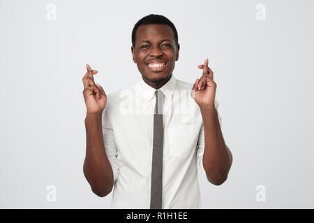 Junge afrikanische Mann, einen Wunsch auf weißem Hintergrund. Ich möchte alles, was ich brauche, zu erhalten. Stockfoto