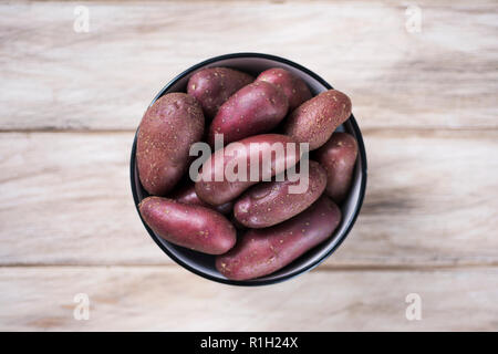 Hohe Betrachtungswinkel von einigen raw-Baby rote Kartoffeln in eine Schüssel geben, auf einem urigen weißer Tisch platziert Stockfoto