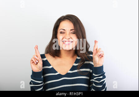 Happy einschrauben bis Augen schöne Frau über ihre Finger, in der Hoffnung, der Wunsch auf blauem Hintergrund. Closeup Portrait Stockfoto