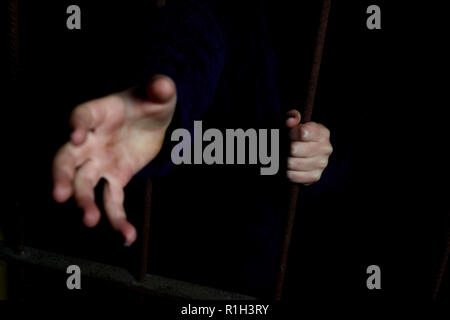 Kind Hände, die Bars in einem dunklen Versteck. Konzept Bild des entführten Kindes Stockfoto